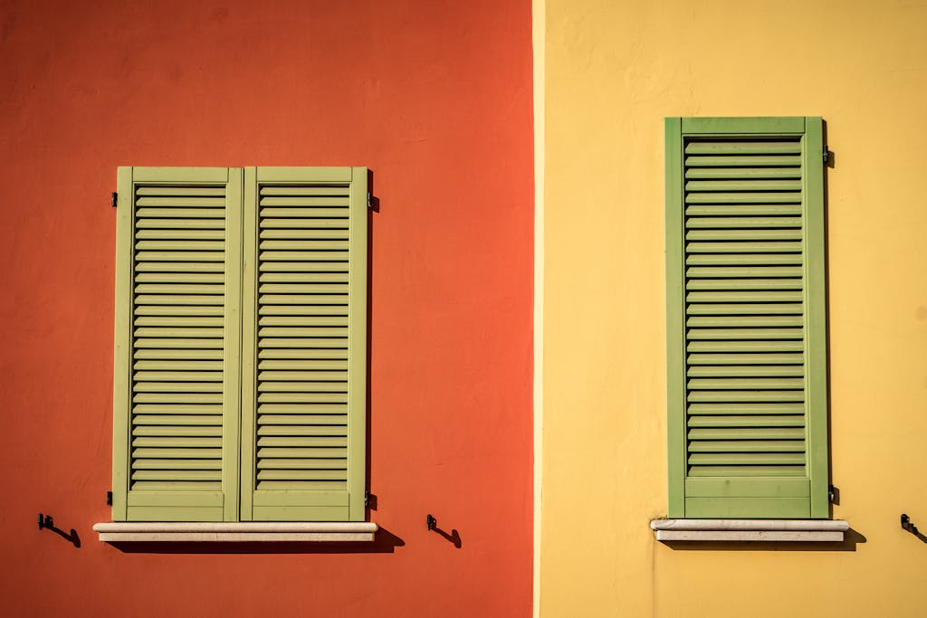 Wohnformen – Nachhaltiges & soziales Wohnen mit Symbiovita (e.V.) 2 Wohnformen – Nachhaltiges & soziales Wohnen mit Symbiovita (e.V.) A vibrant facade with colorful shuttered windows showcasing green louvers on orange and yellow walls.